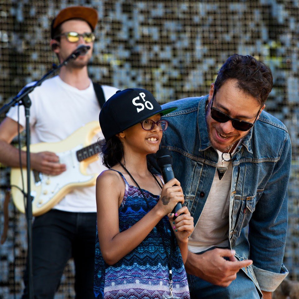 Amos Lee (right) is joined on stage by Melodic Caring Project rockSTAR Maya at a concert at Seattle's Woodland Park Zoo in 2019
